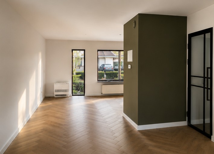 Lege woonkamer met egaal witte muren, wit plafond en olijfgroene accentwand